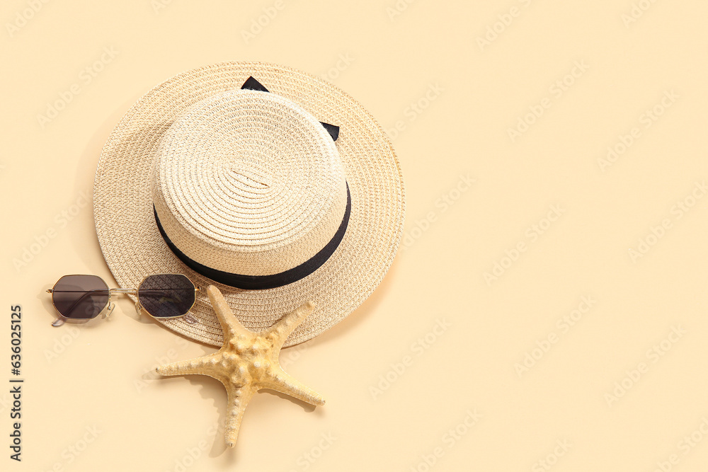 Stylish sunglasses with hat and starfish on beige background