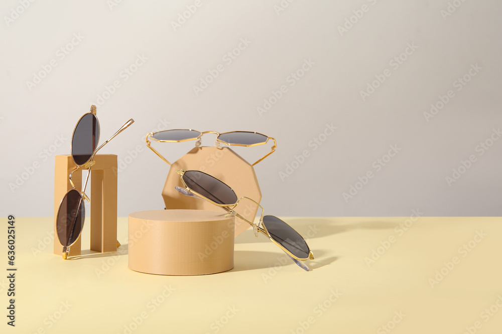 Podiums with different stylish sunglasses on light table