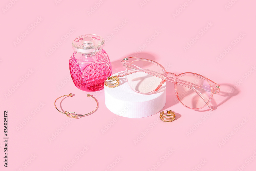 Podium with stylish sunglasses and perfume on pink background