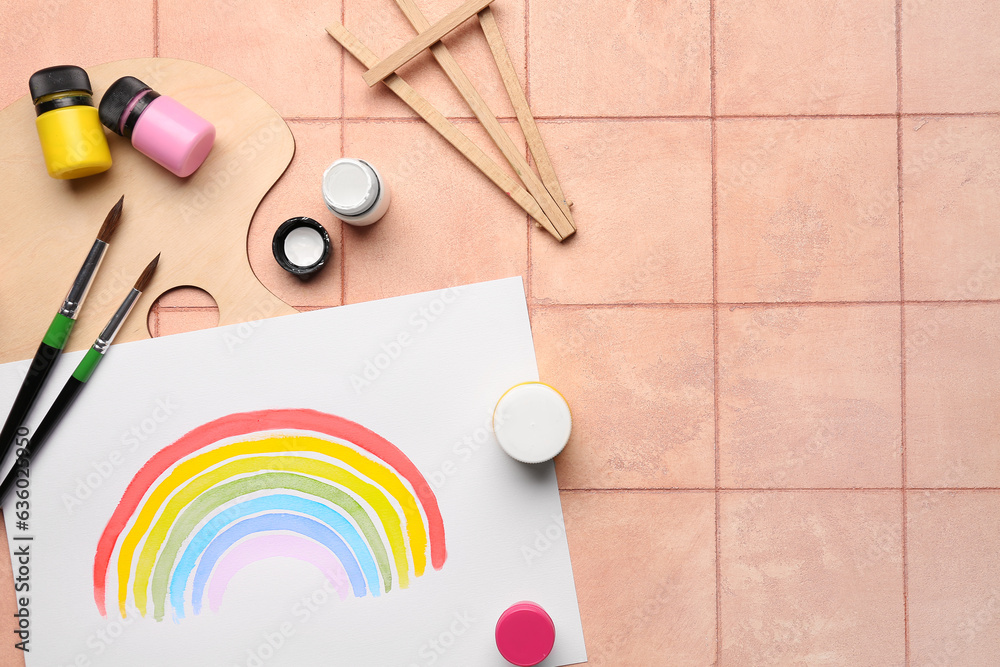 Drawing of colorful rainbow with artists palette, paints and brushes on beige tile background