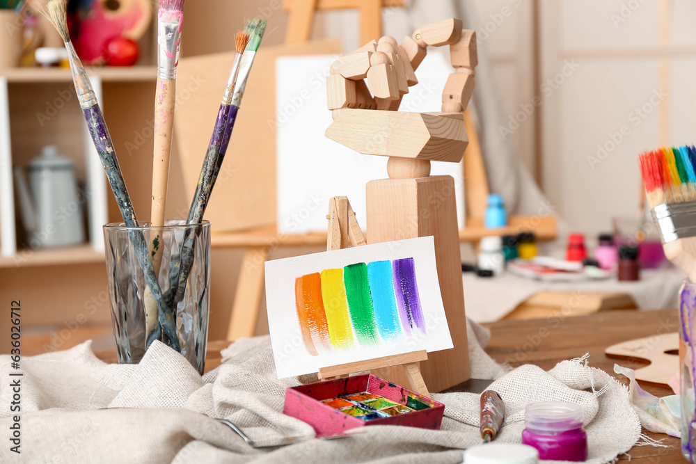 Glass with brushes, paints and mini easel in artists studio