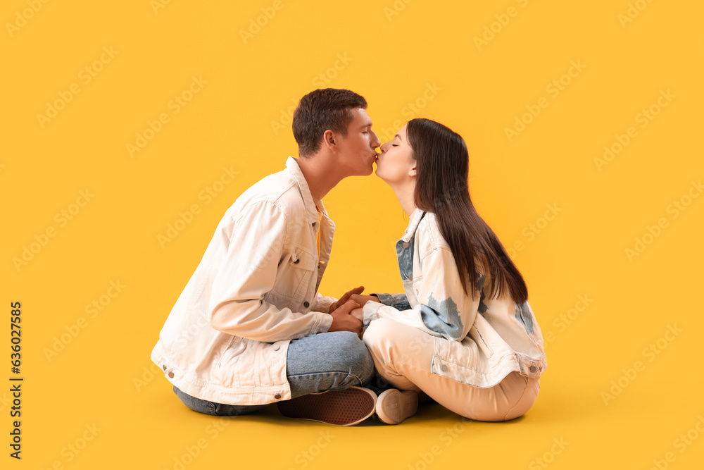 Happy young couple kissing on yellow background