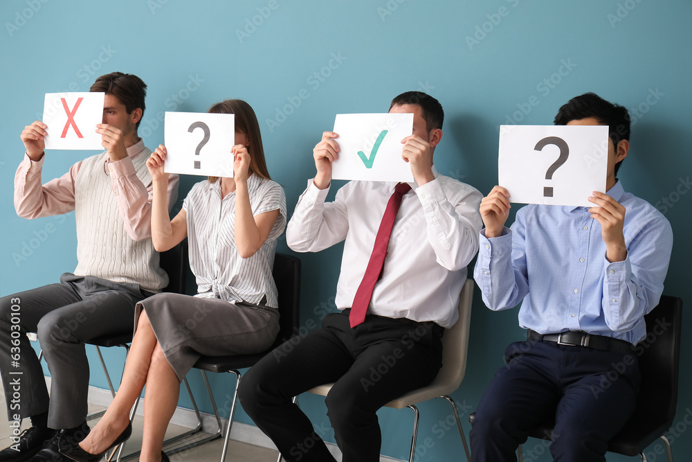 Young applicants holding paper sheets with different marks in room