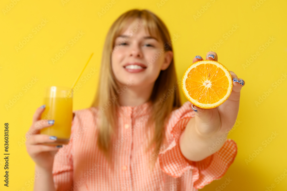 Teenage girl with glass of juice and orange on yellow background, closeup