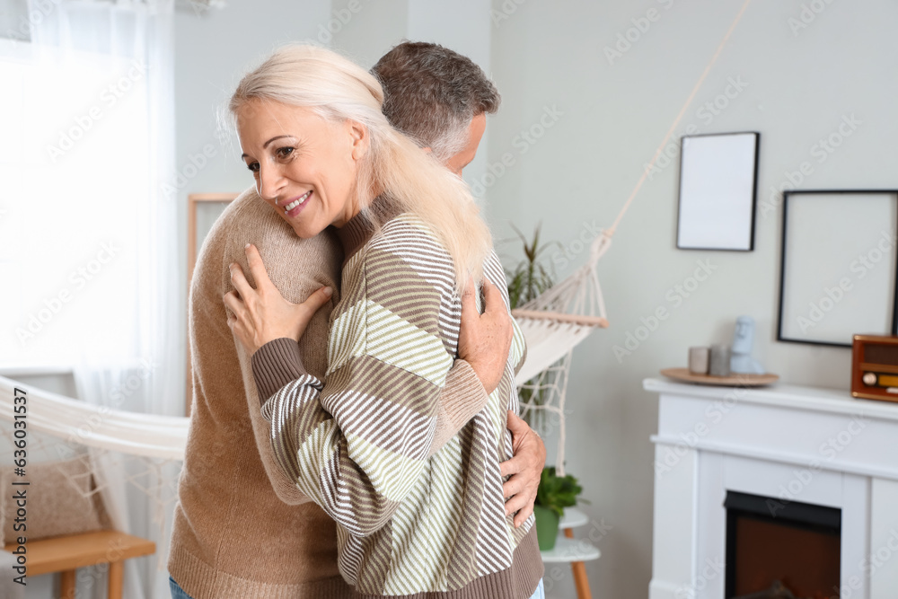 Mature couple dancing near fireplace at home