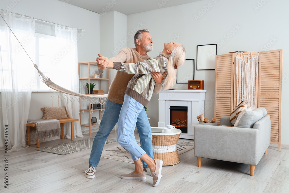 Mature couple dancing near fireplace at home