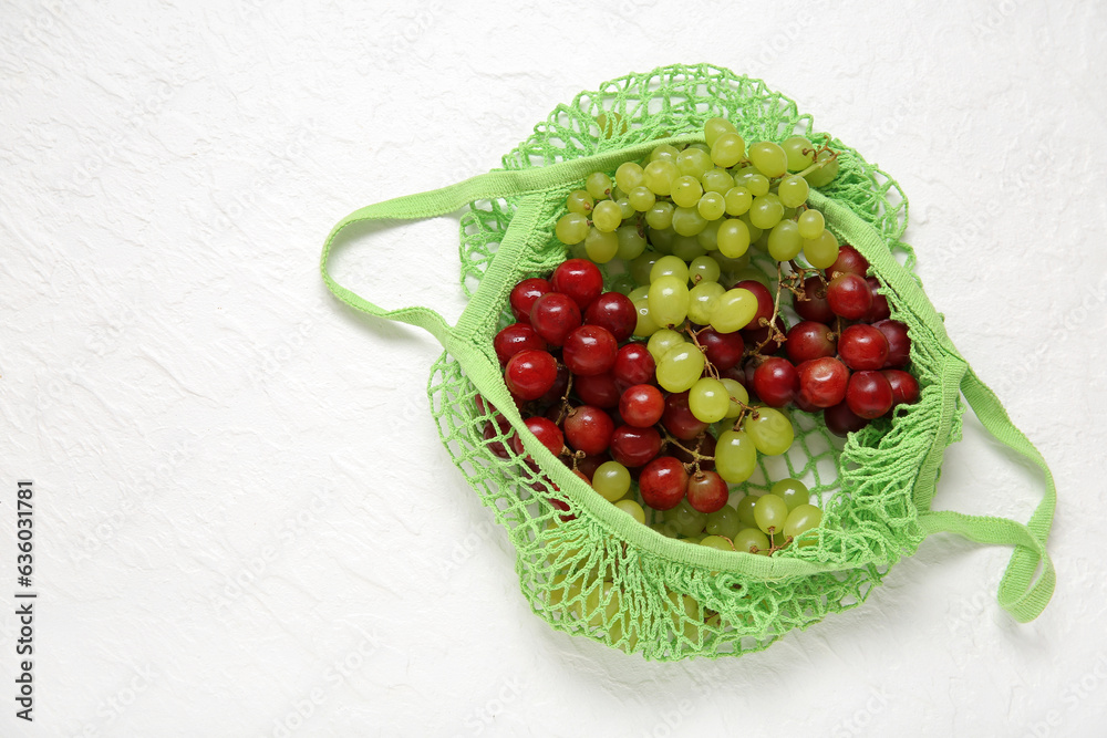 Mesh bag with different fresh grapes on white background