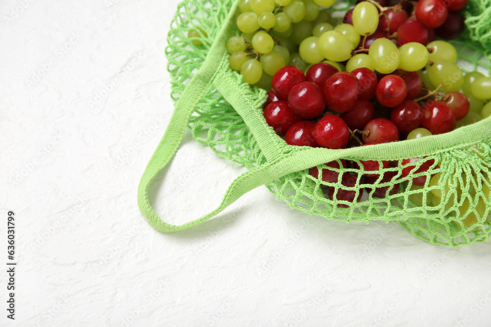 Mesh bag with different fresh grapes on white background, closeup