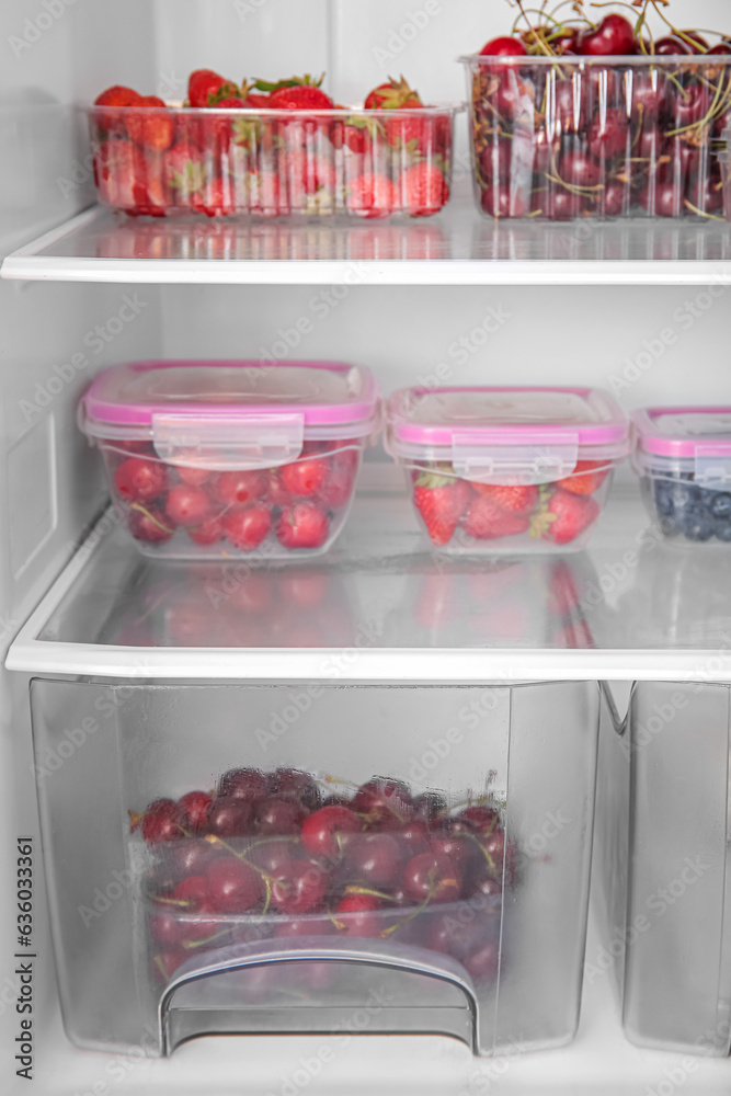 Plastic containers with fresh berries in refrigerator