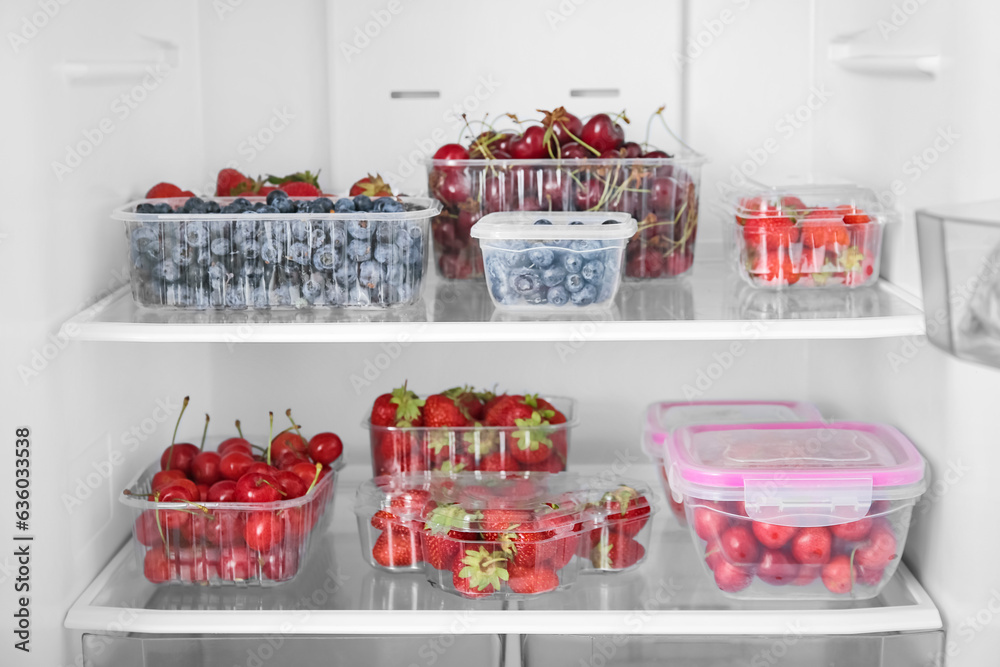 Plastic containers with fresh berries in refrigerator