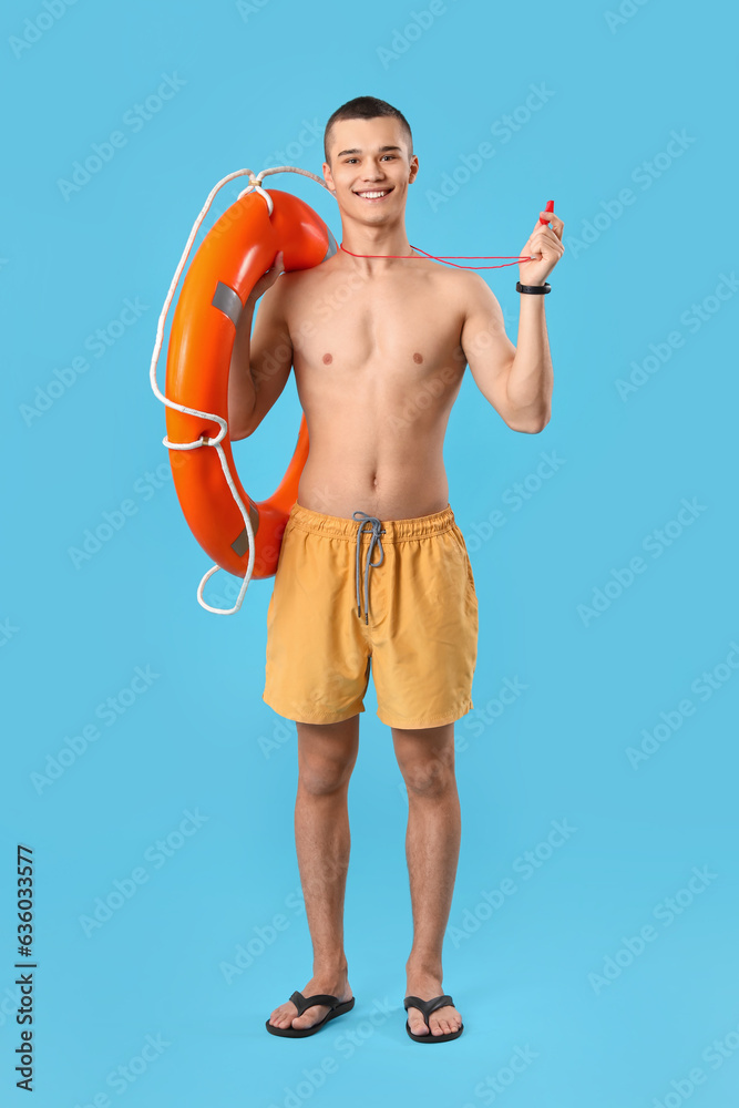 Male lifeguard with ring buoy and whistle on blue background