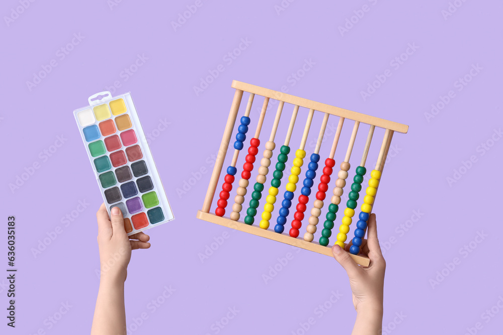 Female hands with abacus and colorful paints on lilac background