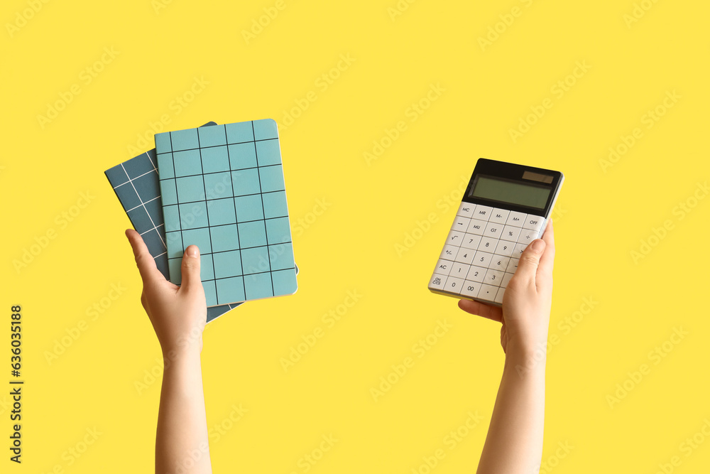 Female hands holding notebooks and calculator on yellow background