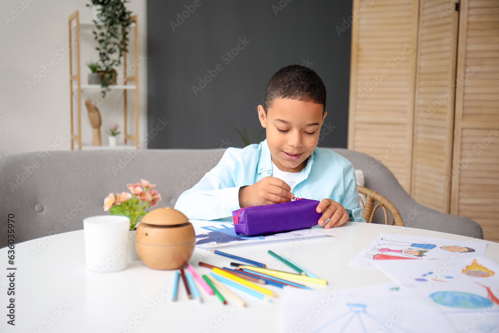 Little African-American boy with pencil case at home