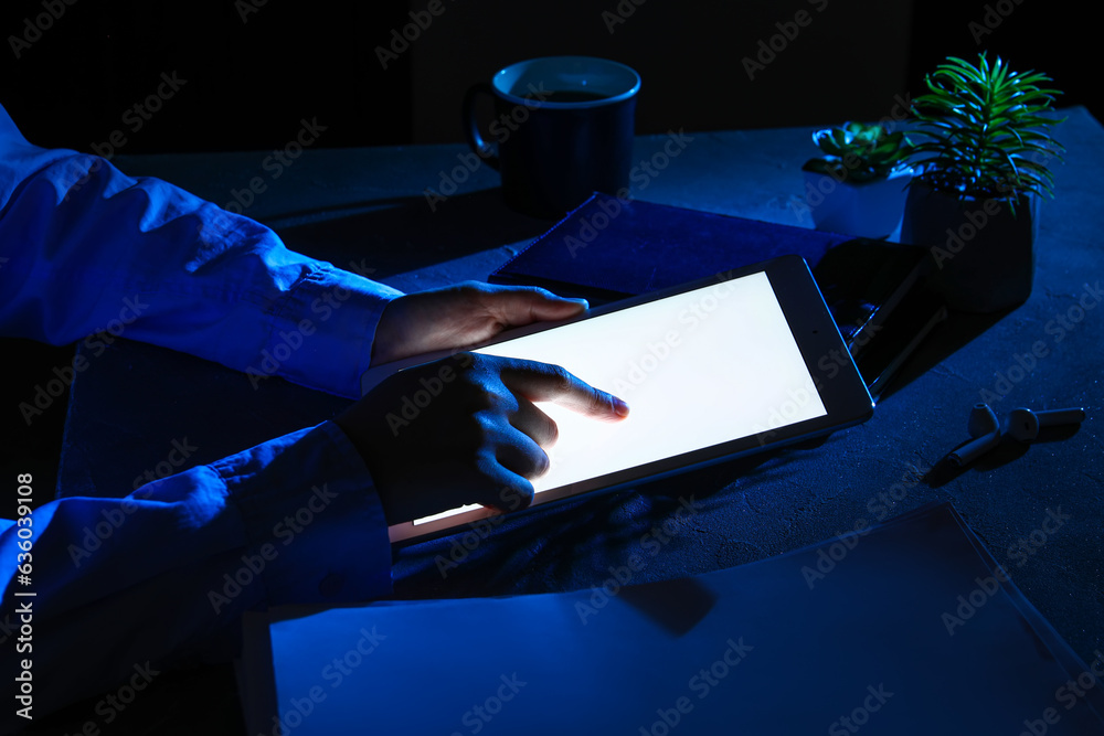 Female programmer working with tablet computer at night in office, closeup