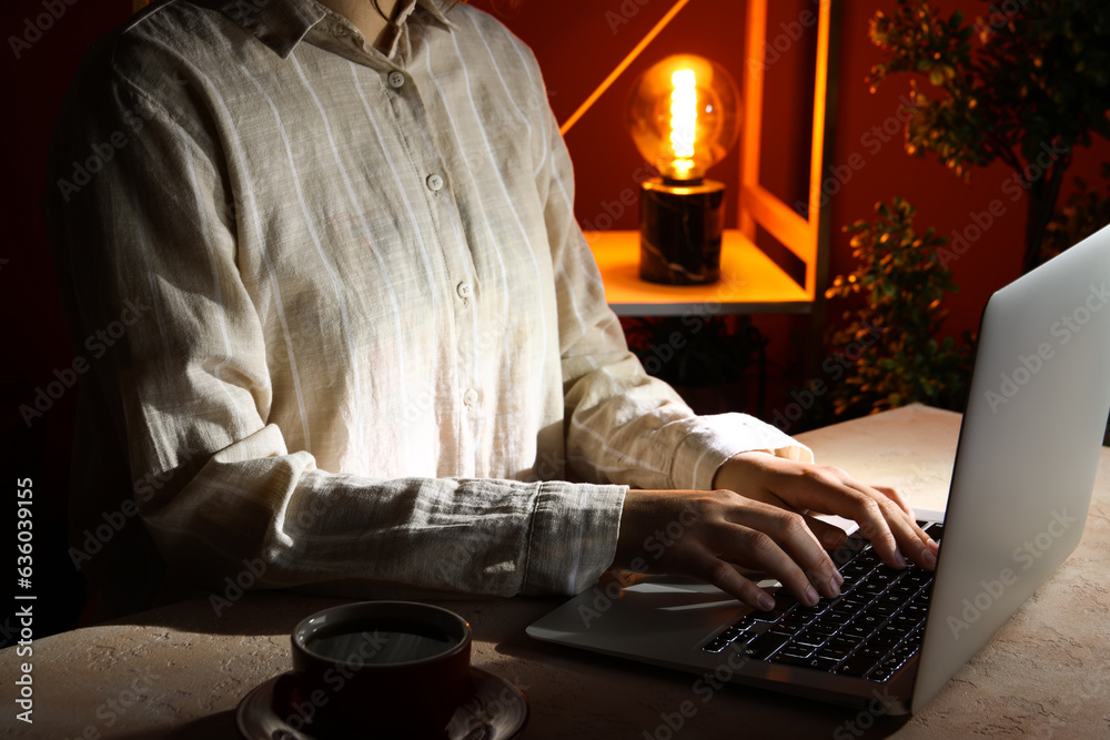 Female programmer typing on laptop keyboard at night in office