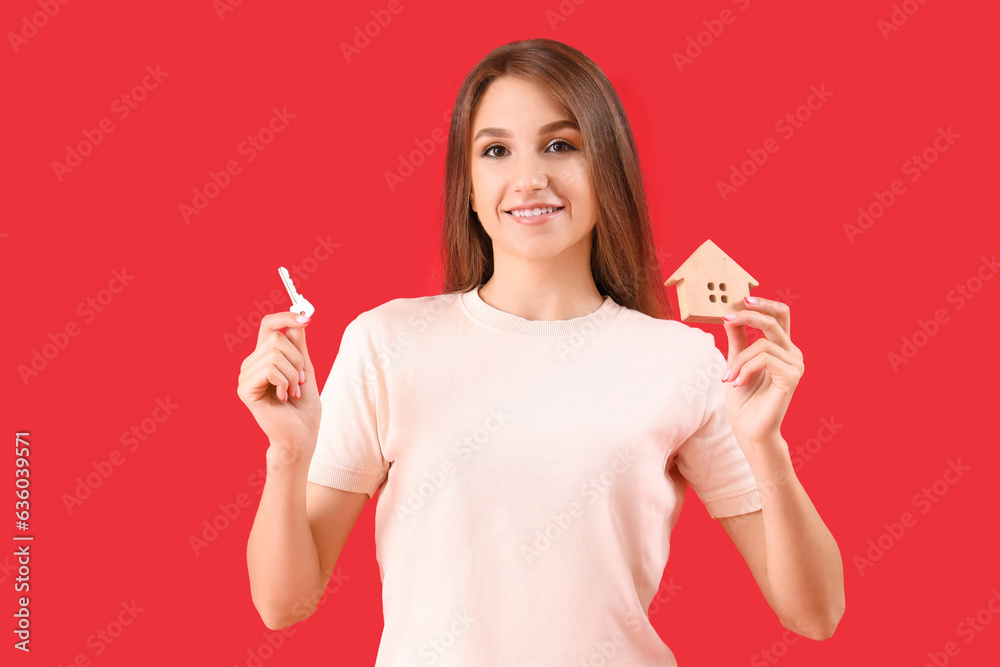 Young woman with key and house figure on red background