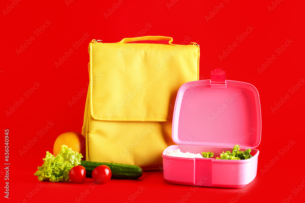 Bag and lunchbox with tasty food on red background