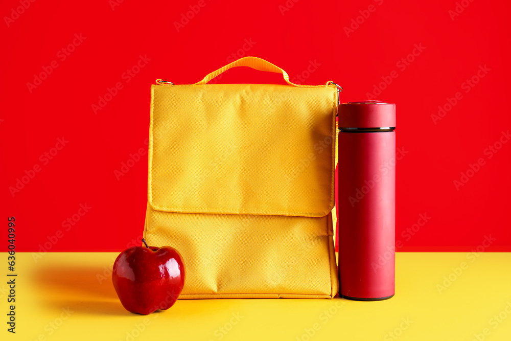 Lunch box bag with thermos and fresh apple on color background