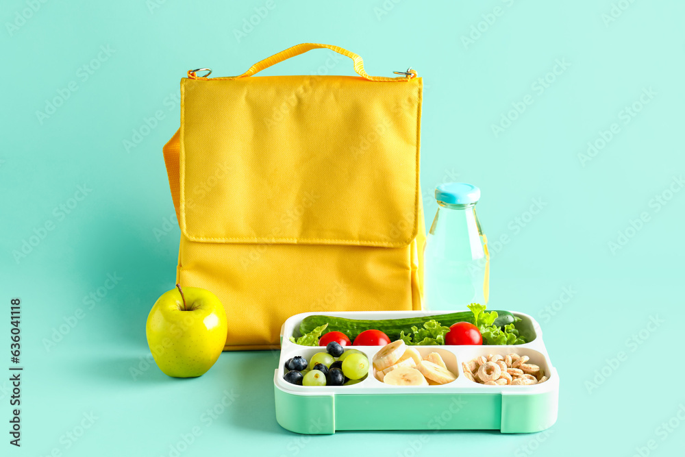 Bag, bottle of water and lunchbox with tasty food on turquoise background