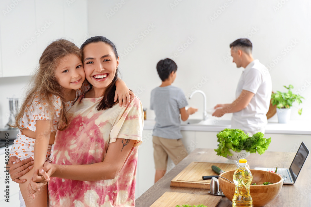 Happy mother with her little daughter hugging in kitchen