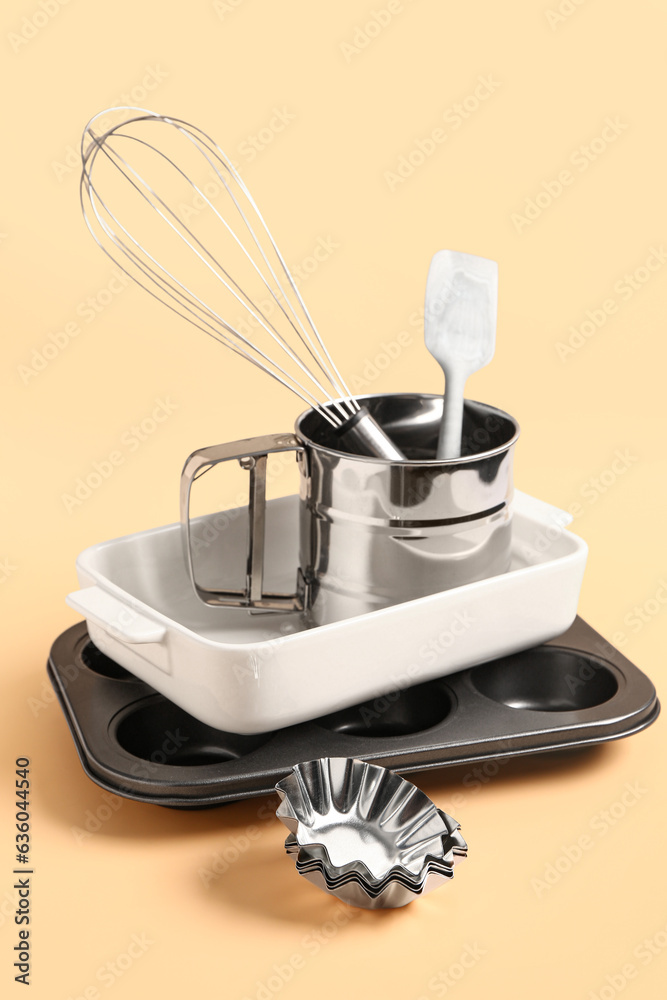 Baking forms and utensils on beige background