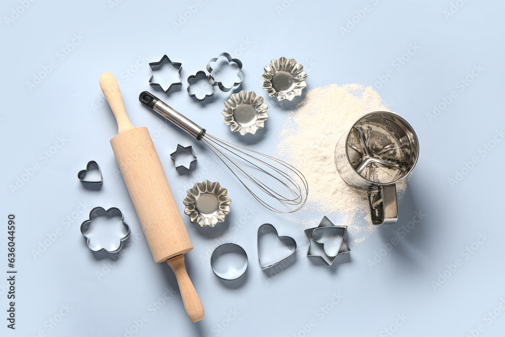 Baking utensils and cookie cutters on blue background