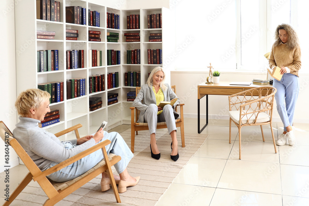 Mature women reading books at home library