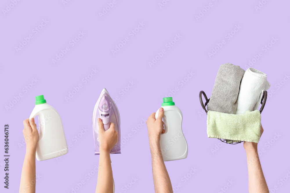 People with bottles of laundry detergent, iron and clean towels on lilac background