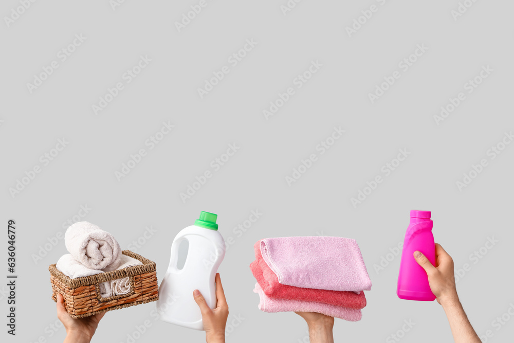 People with bottles of laundry detergent and clean towels on light background