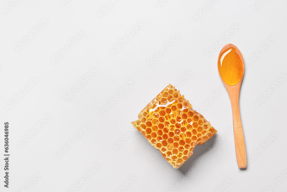 Wooden spoon with sweet honey and comb on grey background