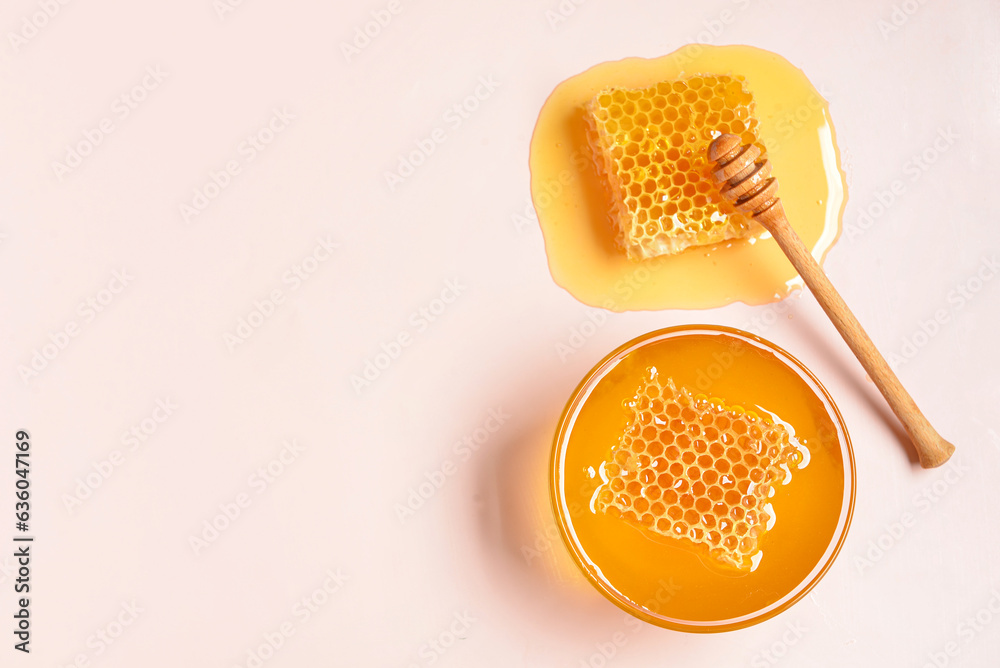 Glass bowl with sweet honey and combs on pink background