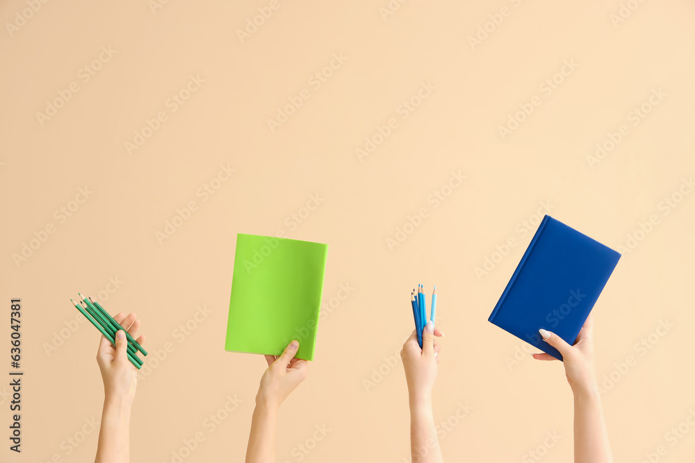 Female hands holding pencils and notebooks on beige background