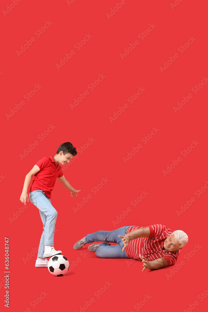 Little boy with his grandfather playing football on red background