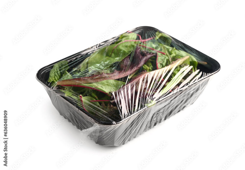 Fresh salad leaves covered with plastic food wrap on white background