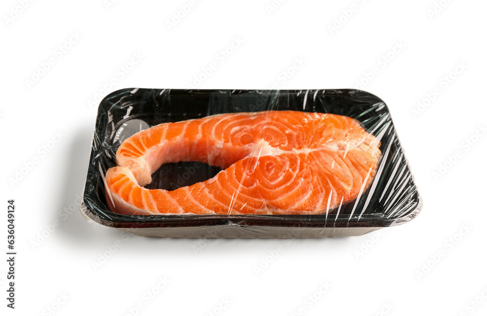 Fresh salmon steak in plastic food wrap on white background