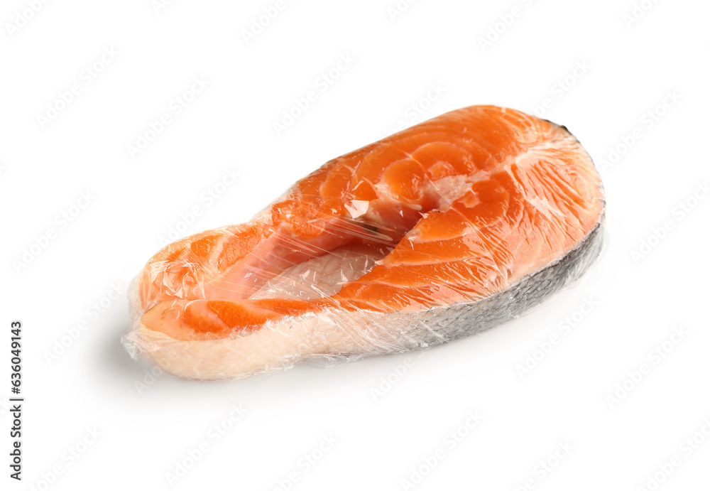 Fresh salmon steak in plastic food wrap on white background