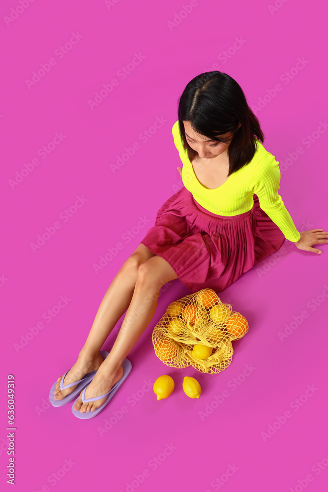 Beautiful Asian woman in summer clothes and with eco bag on magenta background