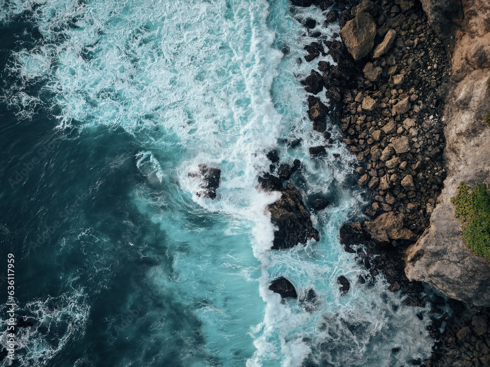 Top view of ocean waves crashing into big rocks