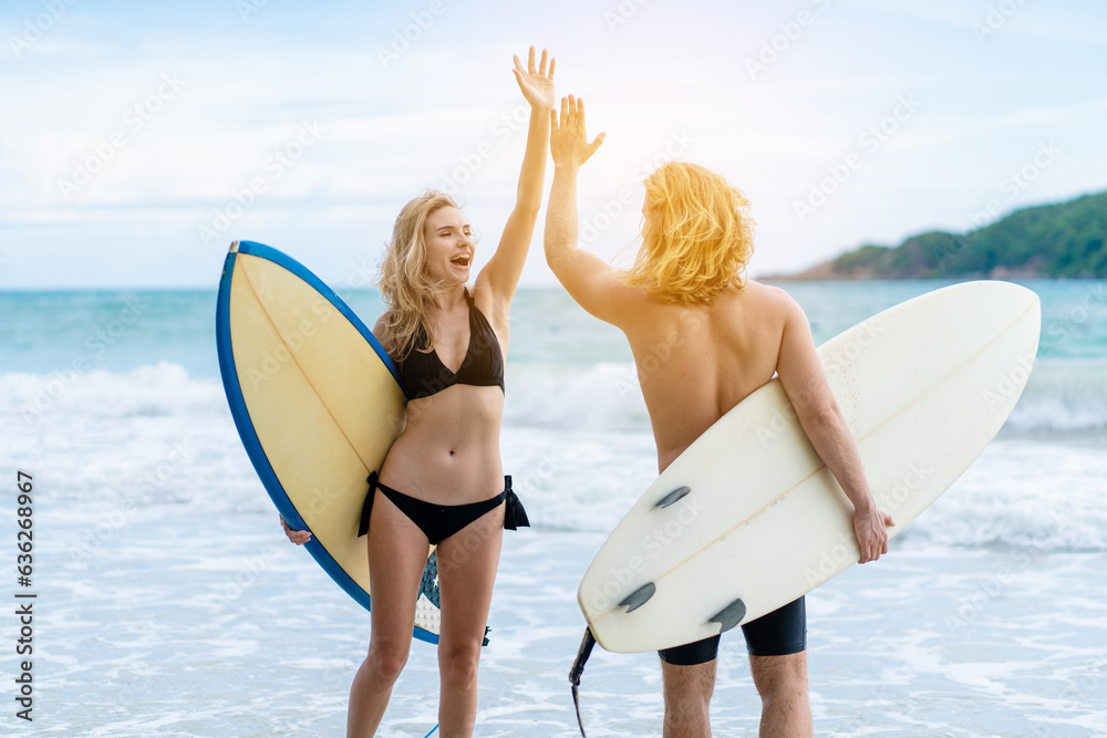 Couple playing surfboard on the beach in weekend activity, Sport extreme healthy lifestyle concept.