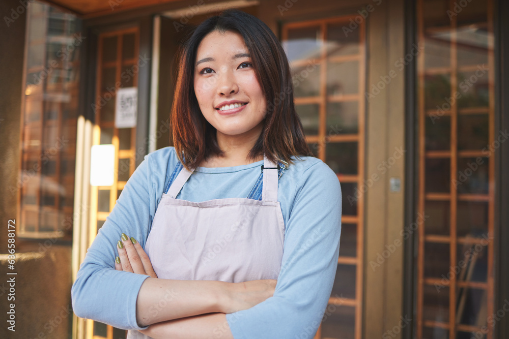 Happy, waitress and Asian woman with arms crossed at restaurant, coffee shop or startup store. Idea,