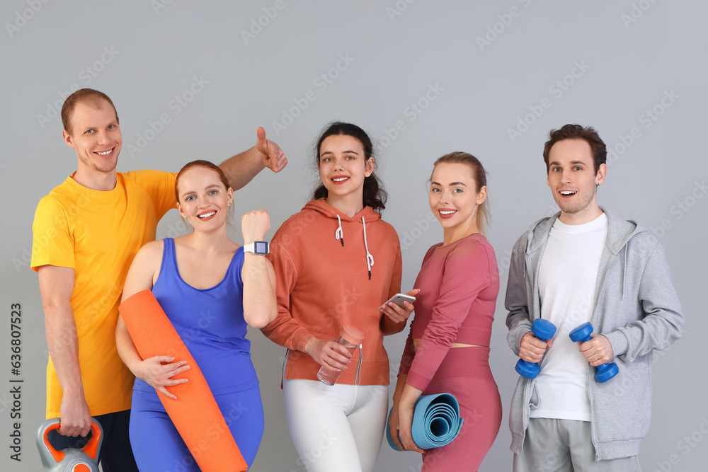 Group of sporty young people with equipment on grey background