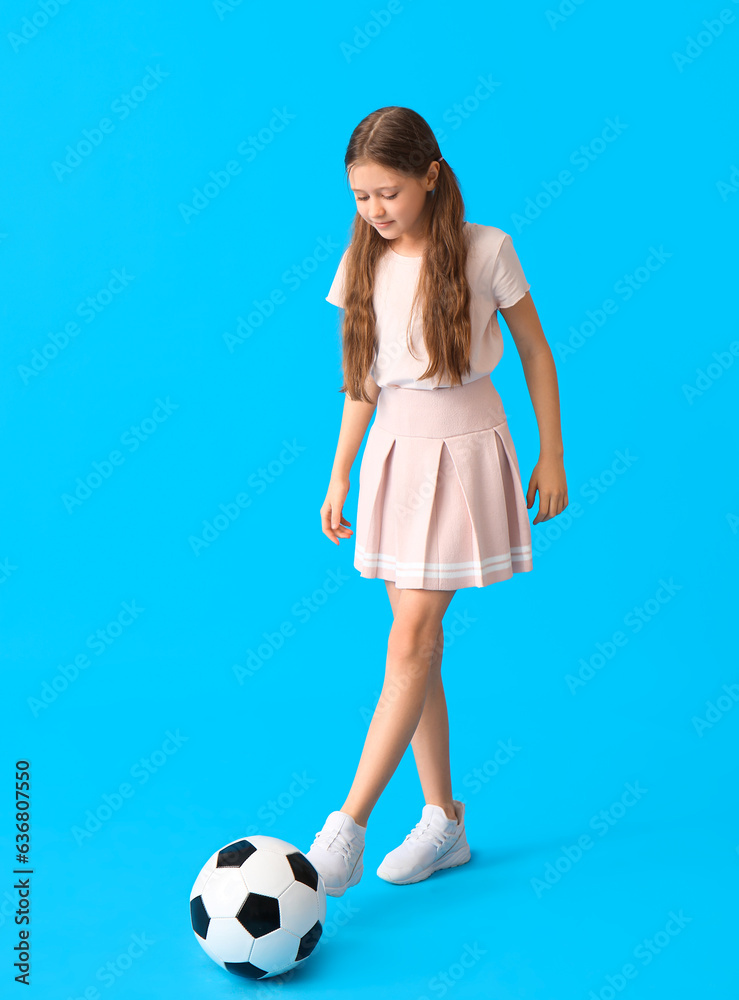 Little girl playing with soccer ball on blue background