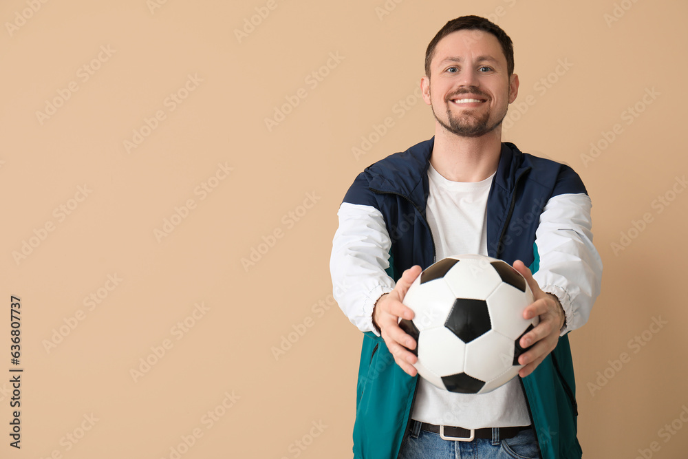 Happy man with soccer ball on beige background