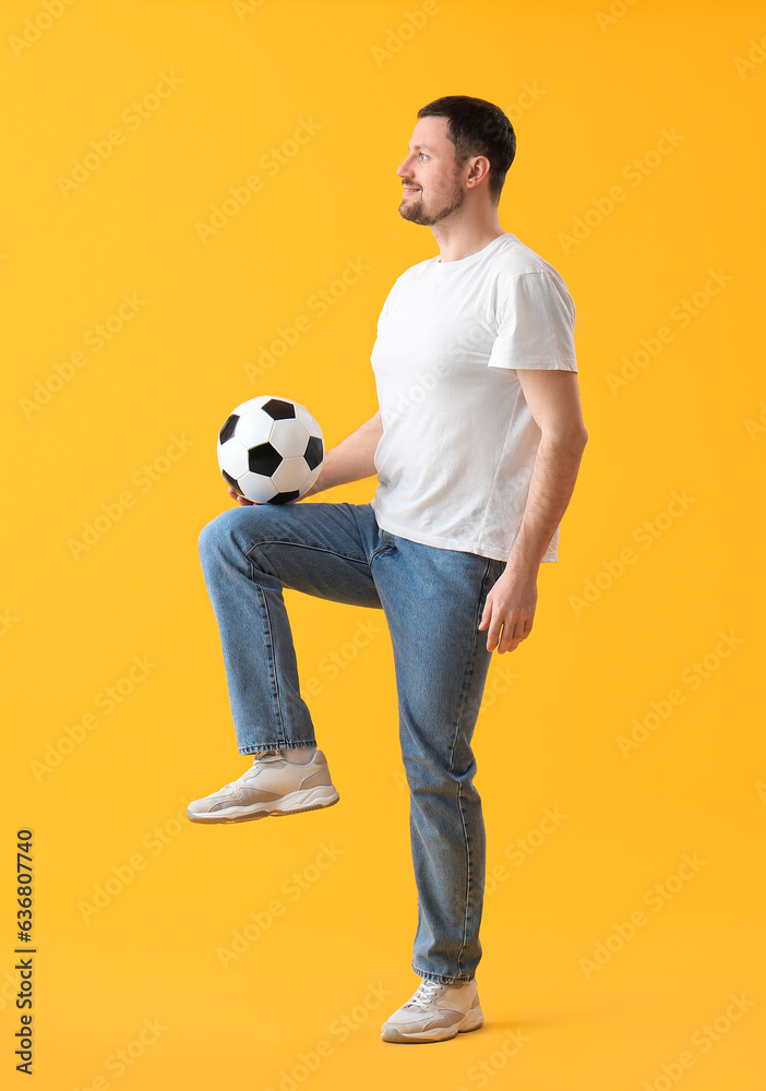 Man playing with soccer ball on yellow background