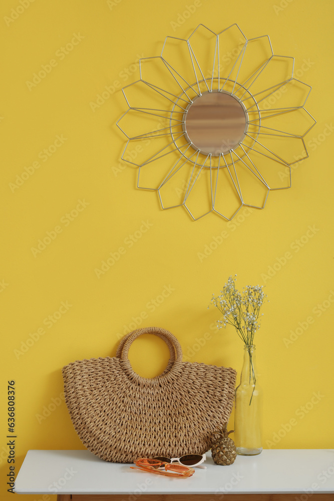 Interior of stylish hallway with mirror, wicker bag and vase on console table