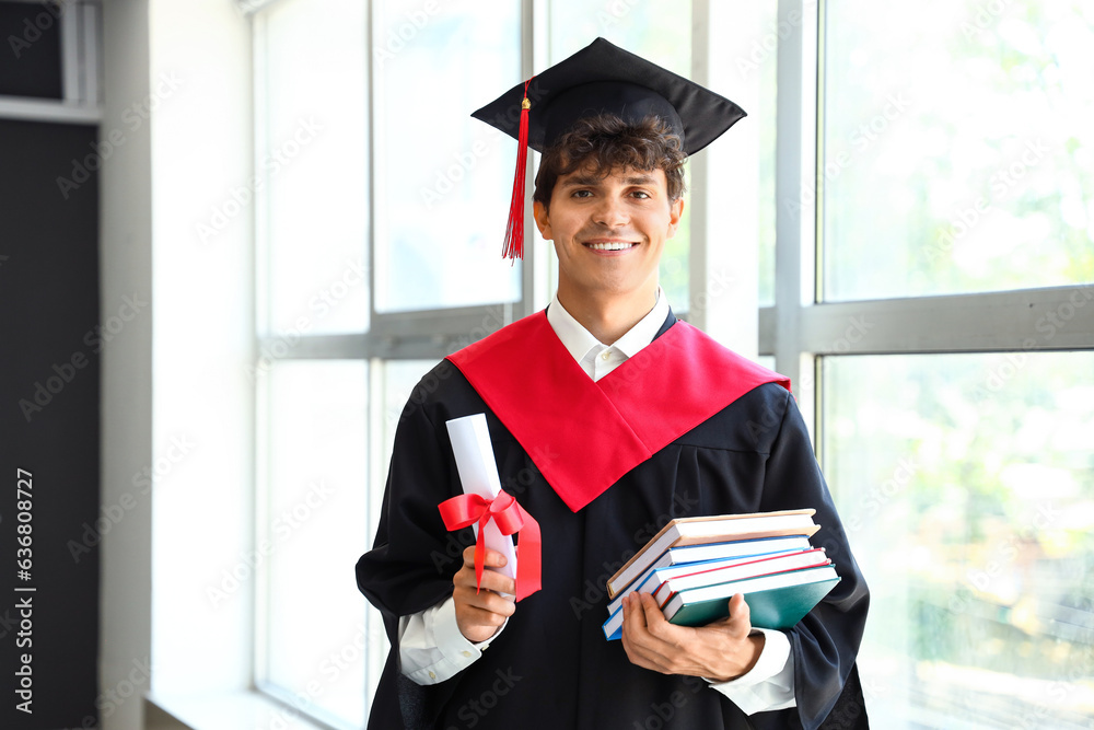 Male graduate student with diploma and books near window in room