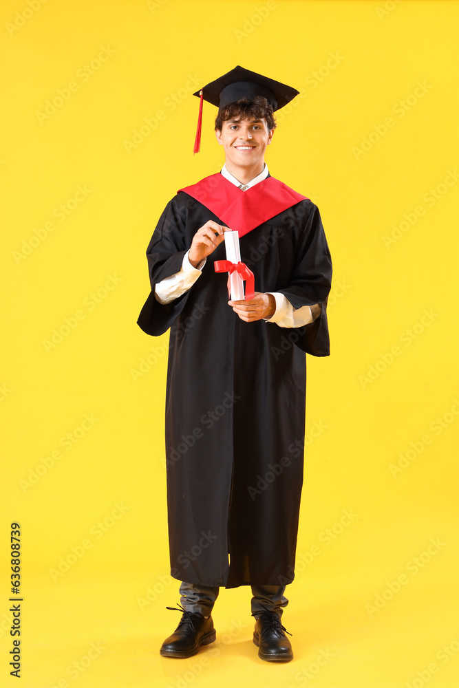 Male graduate student with diploma on yellow background