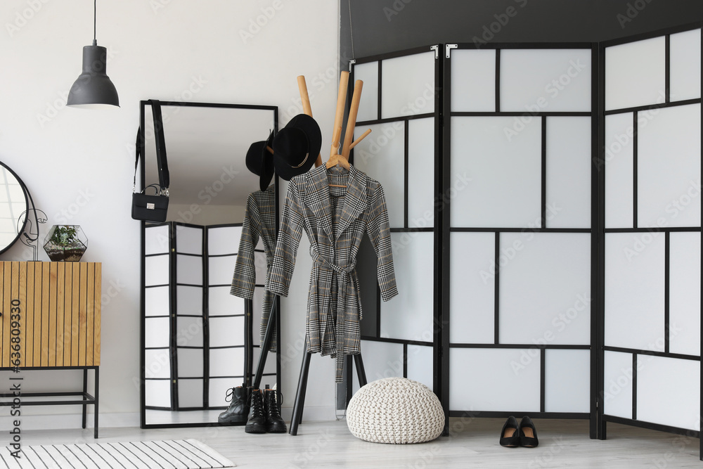 Interior of light hallway with mirror, rack and wooden cabinet