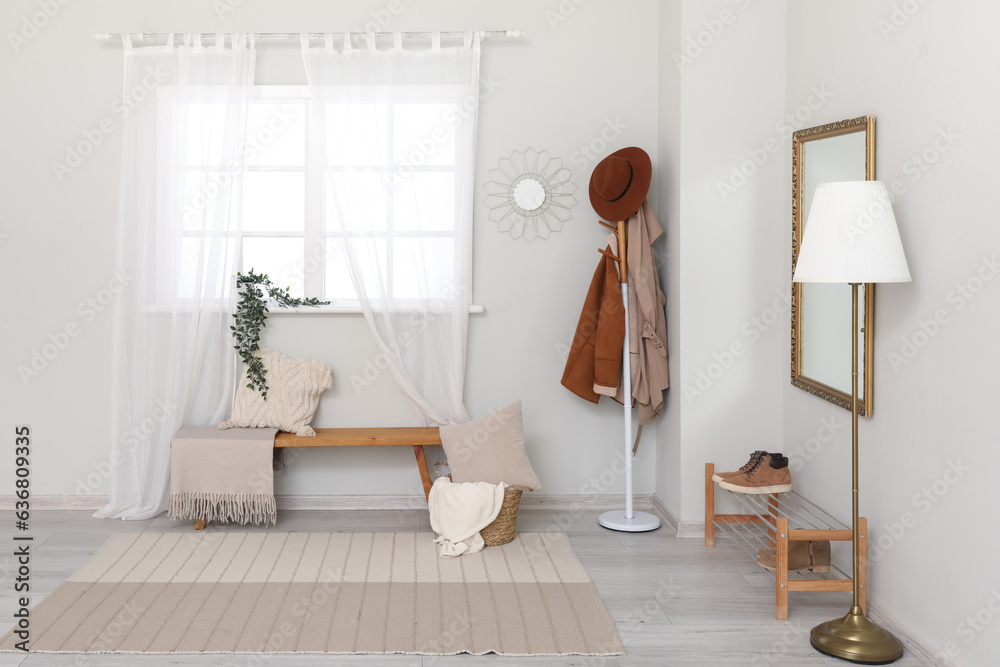 Interior of light hallway with mirror, rack and shoes stand